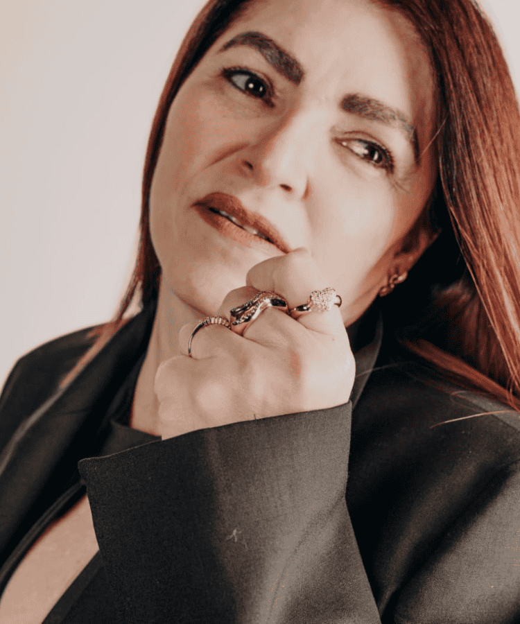Mujer pensativa con anillos, mirando a la distancia.