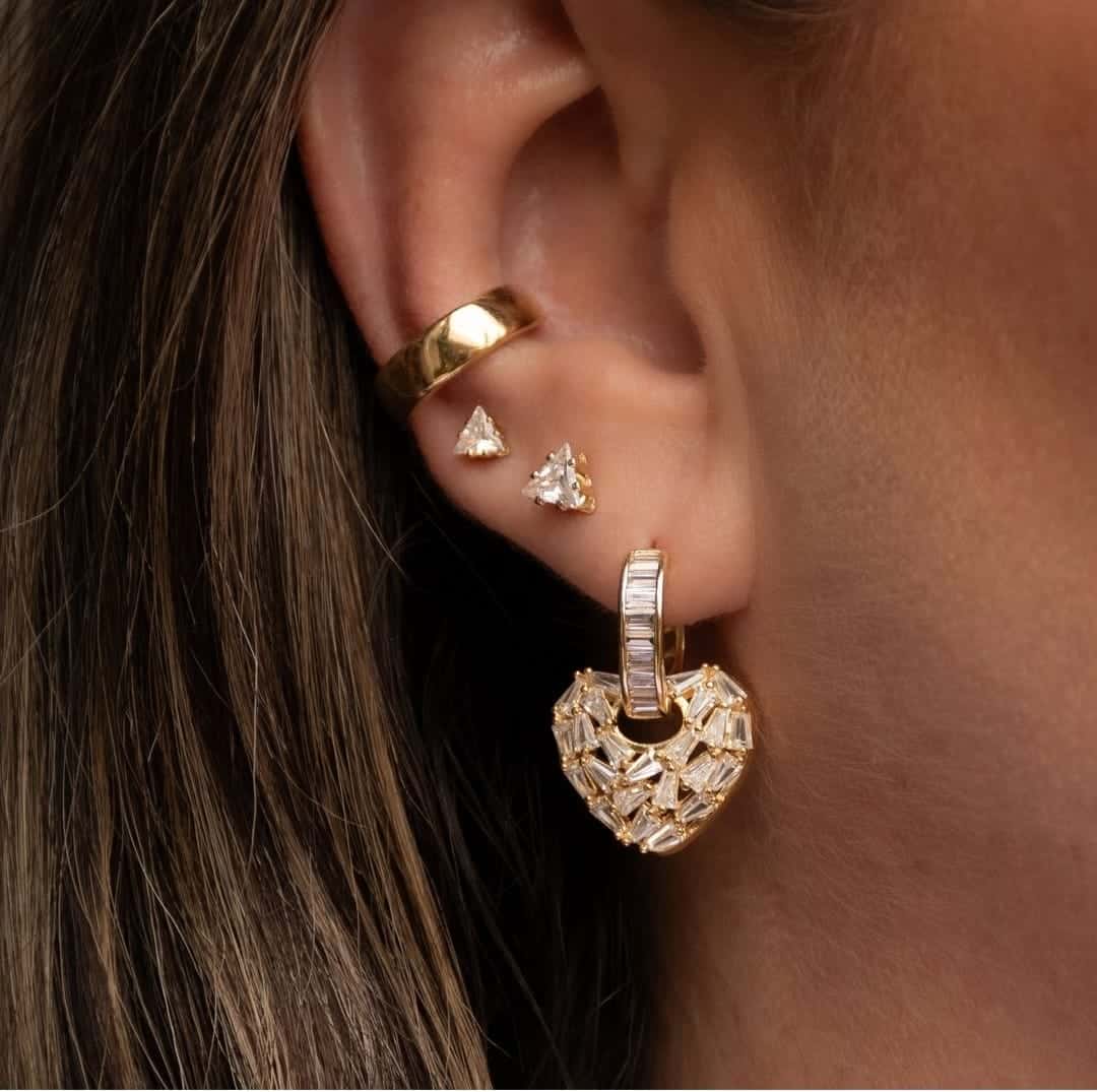 Pendientes dorados y plateados en oreja.