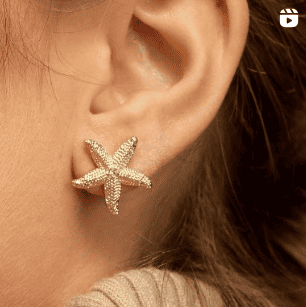Pendiente estrella de mar dorada en oreja femenina