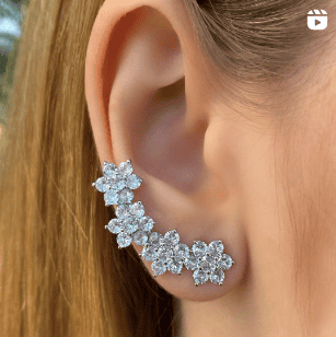 Pendientes florales brillantes en oreja femenina elegante.